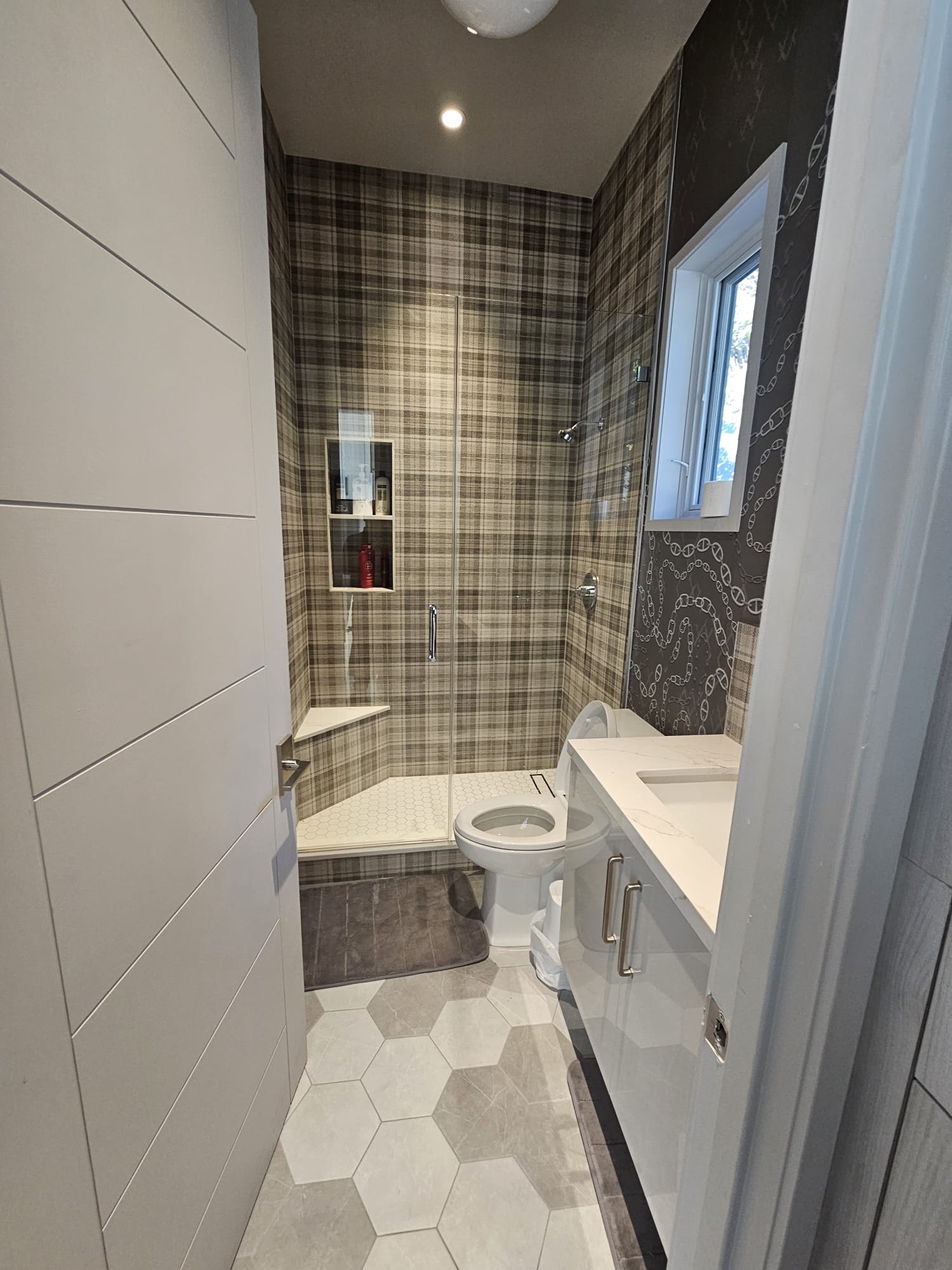 Bathroom remodel with grid-pattern frameless glass shower enclosure and tile surround