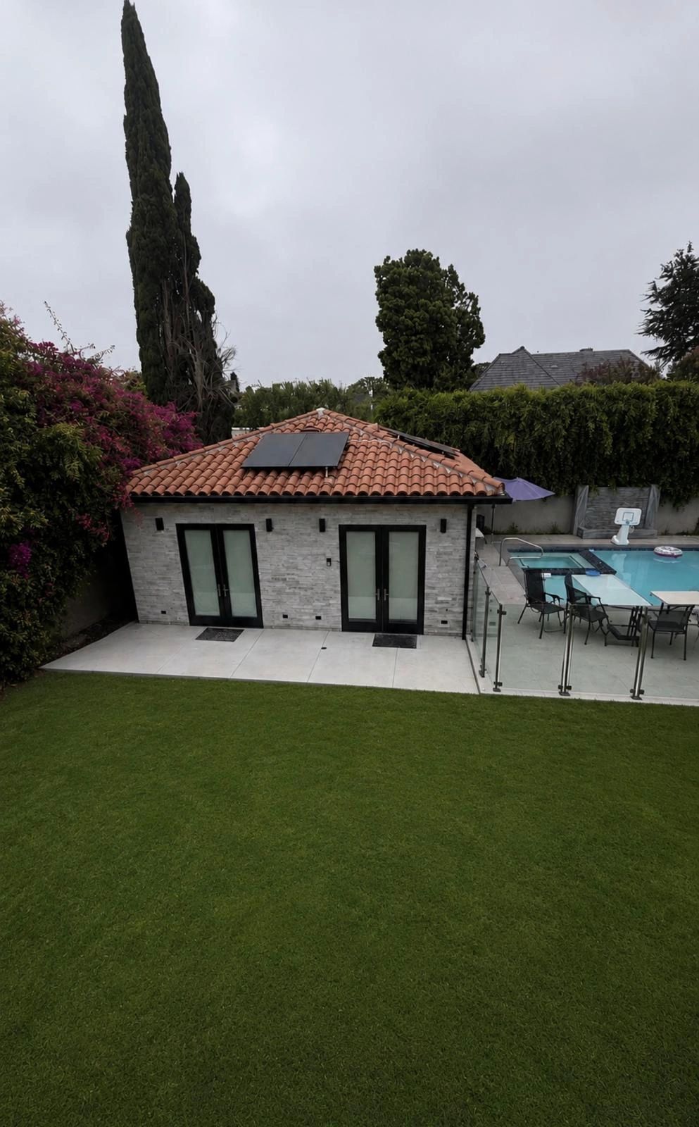 Modern residential pool house with terracotta tile roof and stone exterior