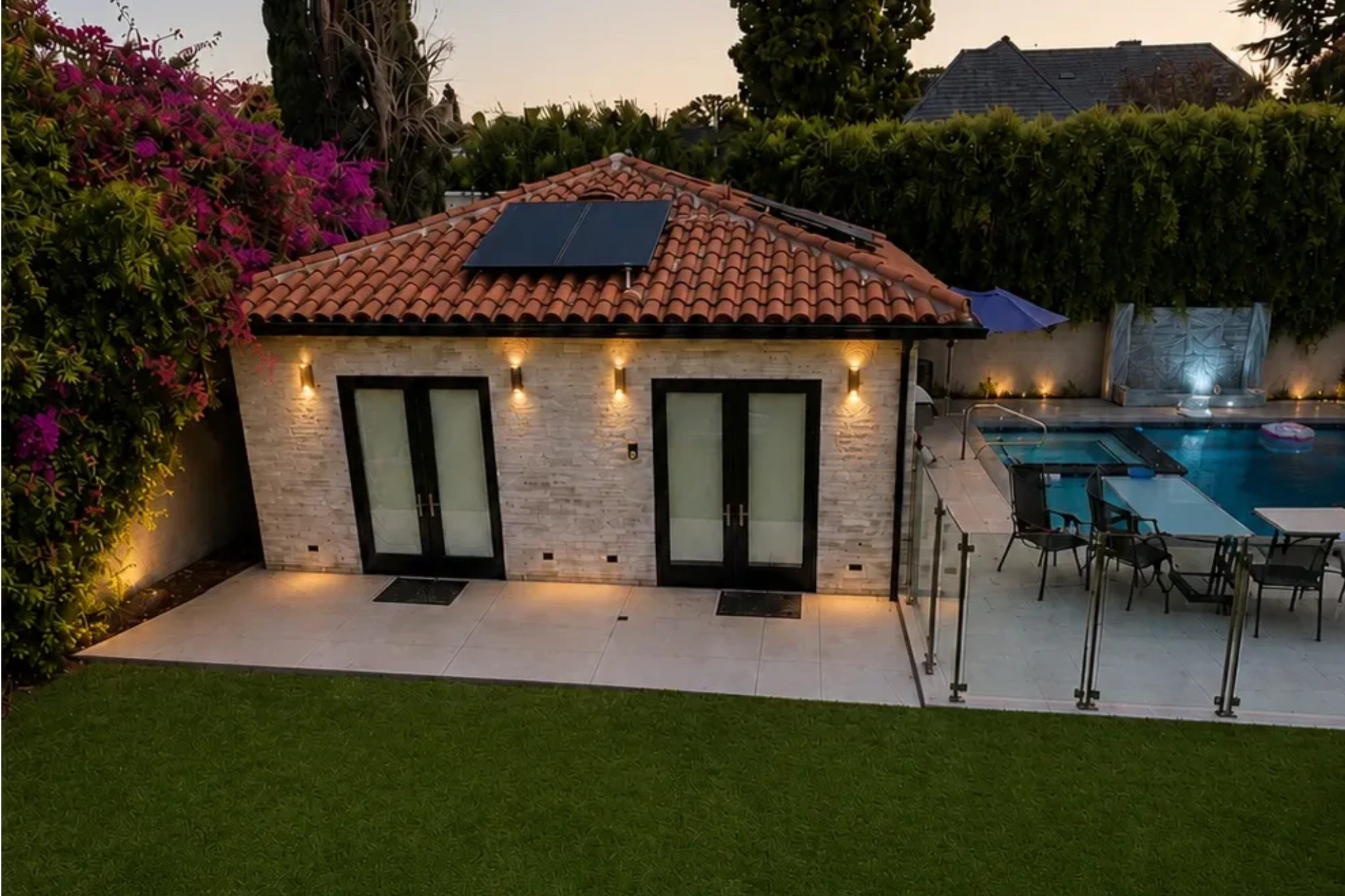 Lush landscaped backyard with mature trees and outdoor living area by Green Tech